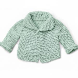 May include: A light green, knitted baby cardigan with a shawl collar. The cardigan has long sleeves with rolled cuffs and a simple button closure. The soft, textured knitwear is a pastel green color.