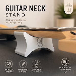 Könnte beinhalten: Weißer, 3D-gedruckter Gitarrenhalsständer, der einen Gitarrenhals trägt. Der Ständer hat ein geschwungenes Design mit einem Rock'n'Roll-Handzeichen. Auf dem Ständer steht "GUITAR NECK STAND" und "Keep your guitar safe and always ready."