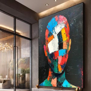 Puede incluir: Gran pintura de retrato abstracto con fondo negro. El rostro está compuesto por formas geométricas coloridas en rojo, azul, naranja y verde. La obra de arte se exhibe en un entorno interior moderno.