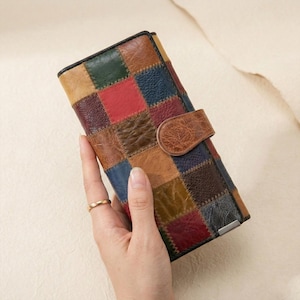 May include: A patchwork leather wallet in a variety of colors, including red, blue, green, and brown. The wallet has a snap closure and a black border. The design is made of squares sewn together.