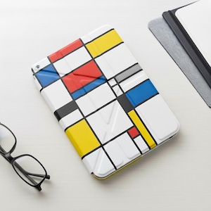 Peut inclure: Une coque de tablette blanche avec un motif géométrique coloré en rouge, jaune, bleu, noir et gris. L'étui est rectangulaire et a une bordure jaune. Des lunettes noires sont à côté de l'étui.
