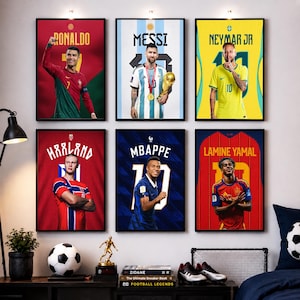 Può includere: Sei poster verticali incorniciati raffiguranti i calciatori Ronaldo, Messi, Neymar Jr, Haaland, Mbappe e Lamine Yamal con le rispettive maglie nazionali, disposti in due file da tre su una parete sopra uno scaffale con decorazioni.