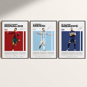 Peut inclure: Trois affiches encadrées représentant les footballeurs Cristiano Ronaldo, Lionel Messi et Kylian Mbappé. Chaque affiche présente un portrait du joueur en tenue d'équipe, avec son nom et sa signature. Les fonds sont rouge, bleu clair et bleu foncé.