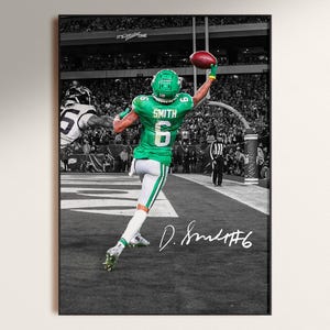 May include: A framed black and white photograph of a football player in a green uniform with the number 6 catching a football. The player is in mid-air, reaching for the ball. The image is signed "D. Smith #6".