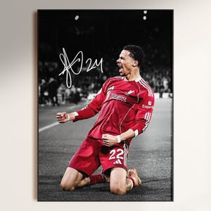 May include: Black and white framed print of a soccer player in a red uniform, kneeling on the field with arms raised in celebration. The player's jersey displays the number 22. The image includes a signature in the upper left corner.