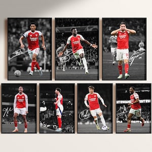 May include: A collection of seven framed prints featuring soccer players in red and white jerseys. Each print showcases a different player in action, set against a black and white stadium background. The players' signatures are visible on each print.