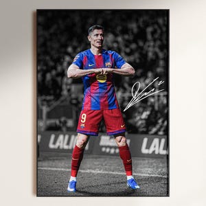 May include: Framed print of a soccer player in a blue and red uniform, with the number 9 visible. The background is a black and white stadium scene. The player is in a celebratory pose, with an autograph in the upper right corner.