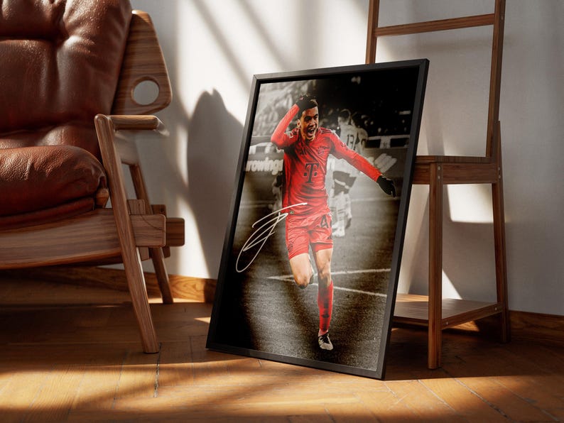 Pode incluir: Impress&atilde;o emoldurada com um jogador de futebol de uniforme vermelho celebrando um gol. A impress&atilde;o tem uma moldura preta e uma assinatura no canto inferior esquerdo. O fundo &eacute; uma imagem em tom s&eacute;pia de um jogo de futebol.