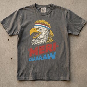 Distressed retro graphic featuring a bald eagle with a squawking open yellow beak and a blonde mullet haircut. The eagle wears a red, white, and blue striped athletic sweatband. Below the illustration, large weathered block text reads "'MERI-" in red, stacked above "CAAAAAW" in bright blue.