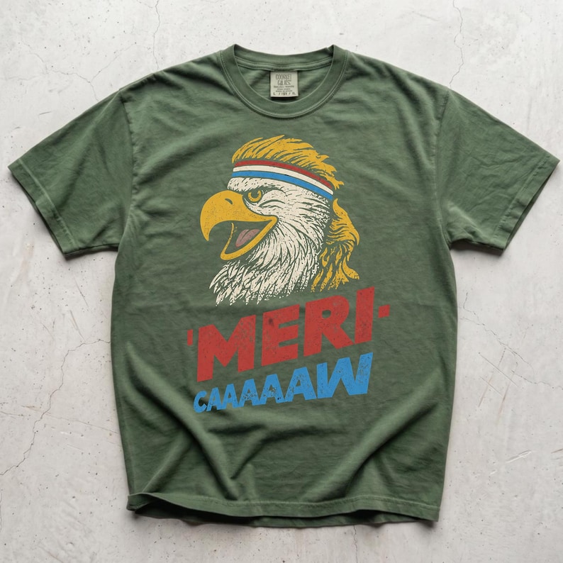 Distressed retro graphic featuring a bald eagle with a squawking open yellow beak and a blonde mullet haircut. The eagle wears a red, white, and blue striped athletic sweatband. Below the illustration, large weathered block text reads "'MERI-" in red, stacked above "CAAAAAW" in bright blue.