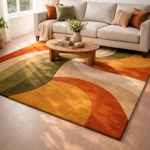 Könnte beinhalten: Ein rechteckiger Teppich mit einem großflächigen, abstrakten Muster aus überlappenden, geschwungenen Formen in den Farben gebranntes Orange, Senfgelb, Olivgrün und Creme. Der Teppich hat einen dichten, strukturierten Flor auf hellem Holzboden.