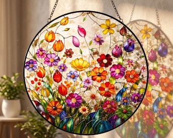May include: A round stained glass window with a black metal frame, featuring a vibrant floral design. The flowers are in shades of red, orange, yellow, purple, and pink, with green leaves. The window hangs from a chain.