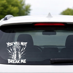 May include: White vinyl car sticker featuring the text "YOU WILL NOT BREAK ME" and a gauntlet design with lightning bolts. The sticker is applied to the rear window of a white car.