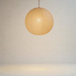 May include: A round, paper lantern with a warm, cream color hangs from a thin cord. The lantern has a ribbed design, and the light source inside creates a soft glow. The background is a neutral, off-white color.