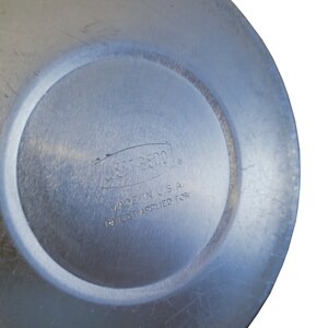 Puede incluir: Una tapa de metal plateado con el texto "Est. 1970" y "Made in U.S.A. Patent Applied For" impreso en ella.
