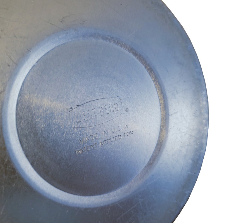 Puede incluir: Una tapa de metal plateado con el texto "Est. 1970" y "Made in U.S.A. Patent Applied For" impreso en ella.
