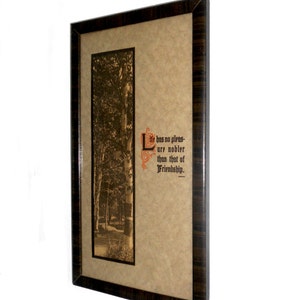Puede incluir: Obra de arte enmarcada con una escena de bosque en tonos sepia. El marco marr&oacute;n oscuro tiene un patr&oacute;n de vetas de madera. La obra incluye la cita: "Life has no pleasure nobler than that of Friendship."