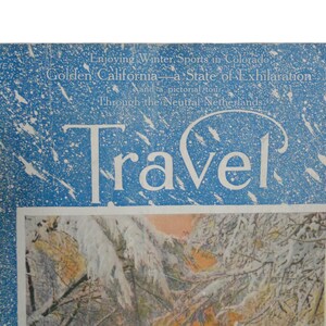 Pu&ograve; includere: Una copertina di rivista vintage con sfondo blu e fiocchi di neve bianchi. La rivista si chiama "Travel" e la copertina presenta il testo "Enjoying Winter Sports in Colorado, Golden California - a State of Exhilaration, Through the Neutral Netherlands."