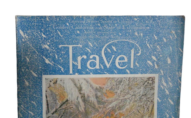 Pu&ograve; includere: Una copertina di rivista vintage con sfondo blu e fiocchi di neve bianchi. La rivista si chiama "Travel" e la copertina presenta il testo "Enjoying Winter Sports in Colorado, Golden California - a State of Exhilaration, Through the Neutral Netherlands."