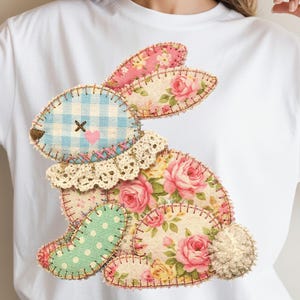 Op de afbeelding: Wit T-shirt met een patchwork konijn ontwerp. Het konijn is samengesteld uit verschillende stofpatronen, waaronder bloemenprints, ruitjes en stippen, met een kanten kraag en een pluizige staart. Het ontwerp is op het shirt gestikt.