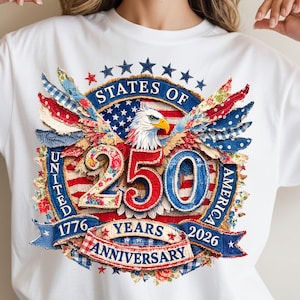 Puede incluir: Camiseta blanca con un diseño patriótico que celebra el 250 aniversario de los Estados Unidos. El diseño incluye un águila, la bandera estadounidense y el texto "STATES OF AMERICA 250 YEARS ANNIVERSARY 1776-2026". El diseño utiliza los colores rojo, blanco y azul.