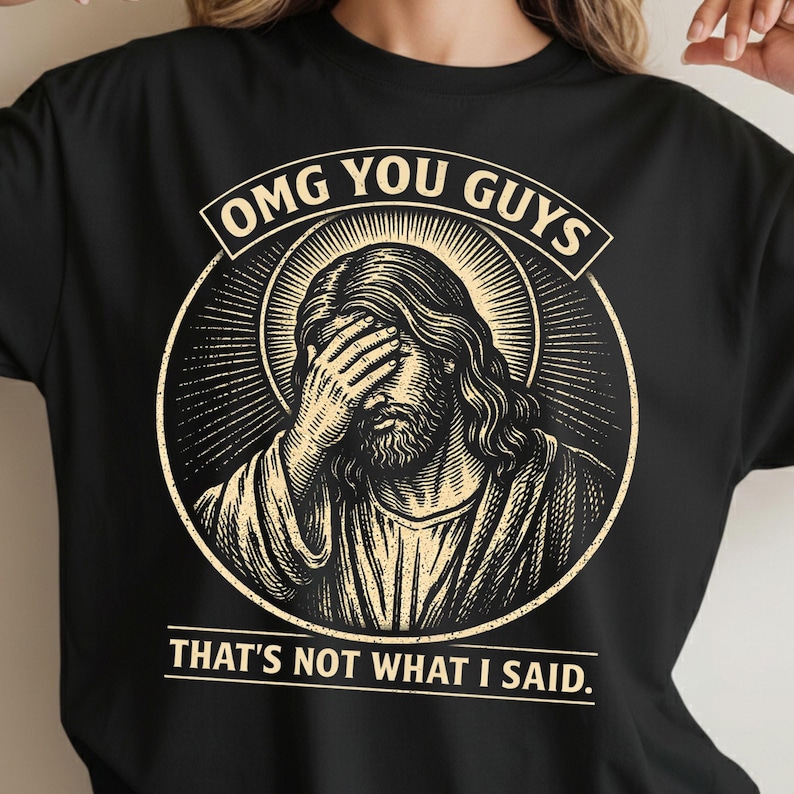May include: Black t-shirt with a distressed graphic of Jesus covering his eyes. The design includes the text "OMG YOU GUYS" above the image and "THAT'S NOT WHAT I SAID" below.