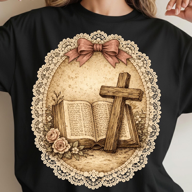 May include: Black t-shirt with a detailed graphic. The graphic features an open book, a wooden cross, and roses, set within a decorative oval frame with a bow. The design has a vintage, sepia-toned aesthetic, evoking a sense of history.
