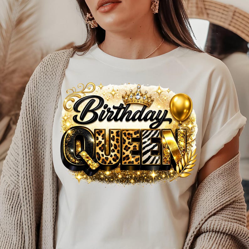 May include: White t-shirt with a gold and black "Birthday Queen" graphic. The design features a crown, balloon, and leopard print letters. The shirt is a casual style.