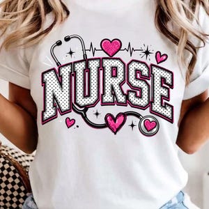 Puede incluir: Una camiseta blanca con la palabra NURSE en letras grandes de bloque con lunares blancos y negros y borde rosa. El dise&ntilde;o incluye un gr&aacute;fico de estetoscopio negro, varios corazones rosas brillantes y peque&ntilde;os destellos.
