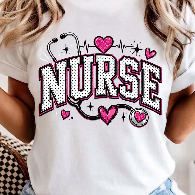 Puede incluir: Una camiseta blanca con la palabra NURSE en letras grandes de bloque con lunares blancos y negros y borde rosa. El dise&ntilde;o incluye un gr&aacute;fico de estetoscopio negro, varios corazones rosas brillantes y peque&ntilde;os destellos.