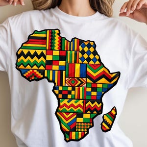 May include: White t-shirt featuring a colorful graphic of the African continent. The continent is filled with various geometric patterns in red, yellow, green, and blue. The shirt is a casual style.