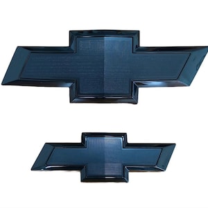 May include: Two black Chevrolet bow tie emblems. The top emblem is larger than the bottom one. Both emblems have a textured center and a glossy black border. The background is white.