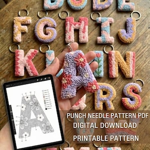 Op de afbeelding: Een verzameling kleurrijke, geborduurde letter sleutelhangers, elk met een goudkleurige ring. De letter "A" wordt in een hand gehouden, met een bloemmotief. Een tablet toont een punch needle patroon. Tekst: PUNCH NEEDLE PATTERN PDF, DIGITALE DOWNLOAD, PRINTBAAR PATROON.
