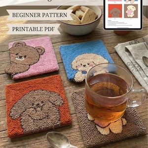 Könnte beinhalten: Handgefertigte Punch-Needle-Untersetzer mit Tiermotiven, darunter ein Bär, ein Hund und ein Welpe. Die quadratischen Untersetzer haben eine strukturierte, geschlungene Oberfläche in Rosa, Blau und Orange. Ein Glas Tee steht auf einem passenden Untersetzer.