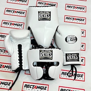 Peut inclure: Un ensemble d'équipement de boxe blanc comprenant deux gants de boxe à lacets, une coquille de protection et un casque. Chaque pièce arbore le logo noir et blanc Cleto Reyes avec l'inscription Hecho en Mexico Professional sur le devant.