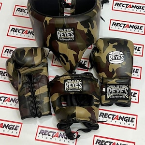 Peut inclure: Un ensemble de boxe Cleto Reyes comprenant une protection inguinale, un casque et deux gants de boxe à lacets, tous dotés d'un motif camouflage. Chaque pièce porte le logo Cleto Reyes avec les inscriptions "Profesional" et "Hecho en Mexico".