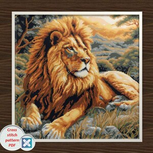 Puede incluir: Patrón de punto de cruz de un majestuoso león descansando en un entorno natural. El león tiene una melena dorada y está tumbado sobre una superficie rocosa con hierba. El fondo presenta una puesta de sol y árboles.