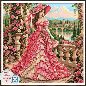 May include: A cross stitch pattern PDF featuring a person in a voluminous pink ruffled gown and a matching wide-brimmed hat adorned with roses, standing on a stone balcony surrounded by pink rose bushes with a river and town in the background.