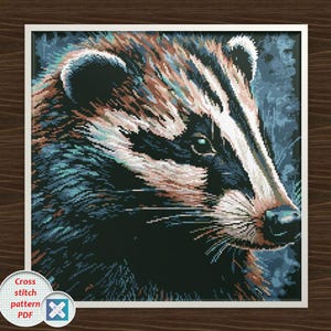 May include: Cross-stitch pattern PDF of a badger. The artwork features a detailed close-up of a badger's face, showcasing its distinctive black and white striped head, brown fur, and piercing green eyes. The image is framed in a white border.