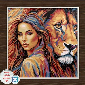 May include: A cross-stitch pattern PDF depicting a woman and a lion. The woman has long, flowing hair and is looking towards the viewer. The lion is positioned behind her, with its face visible. The artwork uses a variety of colours.