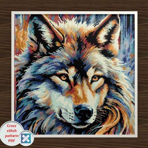 May include: A cross-stitch pattern PDF featuring a detailed portrait of a wolf. The artwork showcases the wolf's face with a mix of colors, including blue, orange, and white. The image is framed in white, with a wooden background.