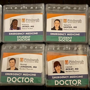 May include: Eight clear plastic ID badges from Pittsburgh Trauma Medical Centre are displayed. Each badge has a photo, name, and title, with the words "Emergency Medicine" and "Doctor" or "Student Doctor" printed on them.