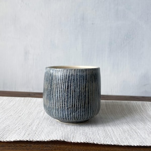 En handgjord teskål i keramik med delikat sgraffito-snideri och matt glasyr - minimalistisk yunomi-kopp