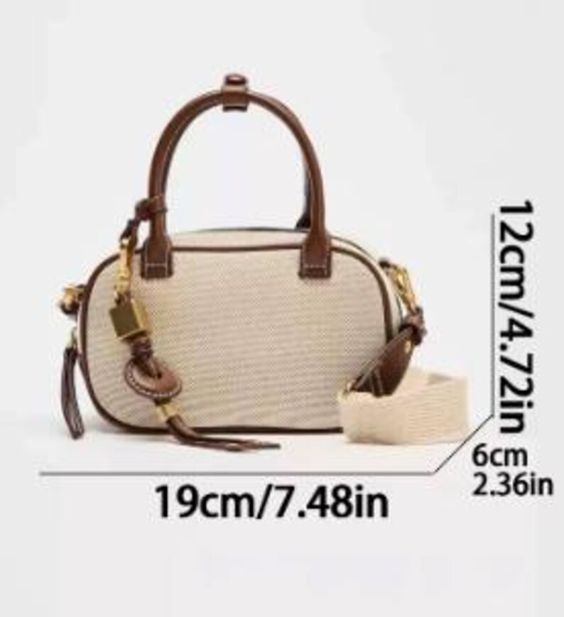 May include: A beige and brown handbag with a top handle and a detachable shoulder strap. The bag is 19cm long, 12cm high, and 6cm wide. It features a brown leather handle and trim, a gold-coloured clasp, and a decorative tassel.