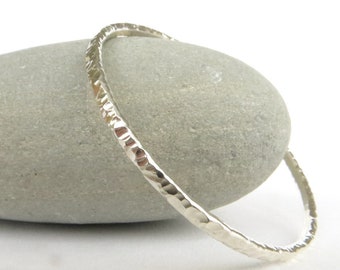 Puede incluir: Un brazalete de plata martillado. El brazalete es simple y elegante, con un acabado liso y pulido.