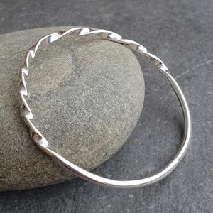 Peut inclure: Un bracelet jonc en argent torsadé. Le bracelet est fait d'un fil épais et torsadé et a une finition lisse et polie.