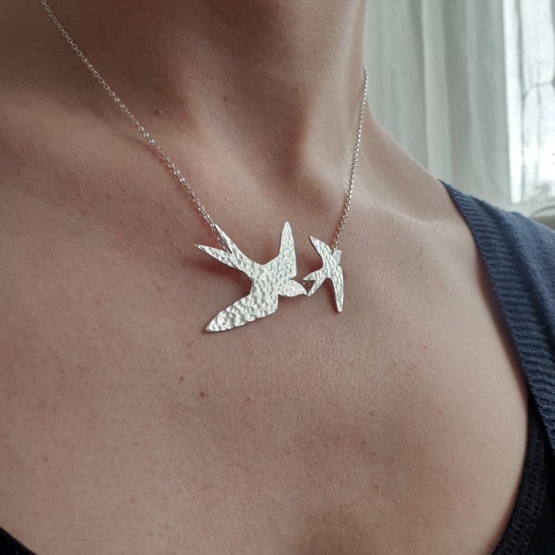 Peut inclure: Un collier en argent avec deux pendentifs en forme d'oiseau en argent martel&eacute;. Les oiseaux se font face et semblent s'embrasser.