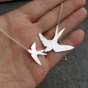 Peut inclure: Un collier en argent avec deux pendentifs en forme d'oiseau en argent martel&eacute;. Les oiseaux volent dans des directions oppos&eacute;es.