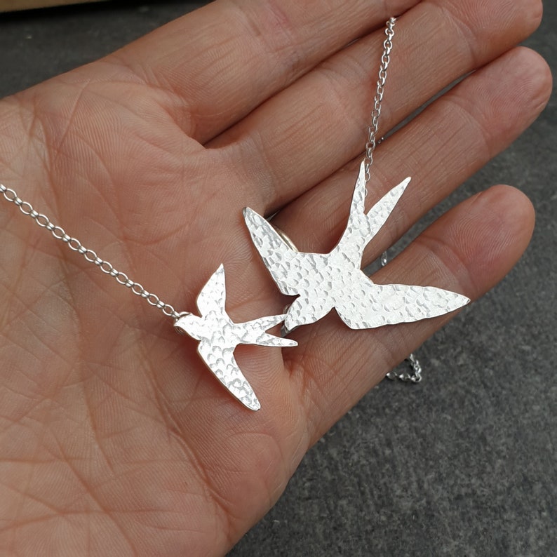 Peut inclure: Un collier en argent avec deux pendentifs en forme d'oiseau en argent martel&eacute;. Les oiseaux volent dans des directions oppos&eacute;es.