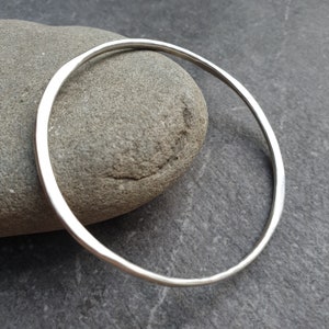 May include: A simple silver bangle bracelet with a hammered finish.